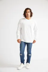 Jean skinny de hombre color negro, ajustado desde la cadera hasta los tobillos, con roturas en las rodillas y logo bordado en el bolsillo trasero.