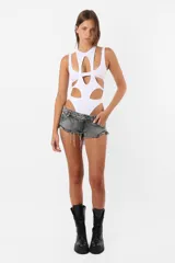 Body blanco de microfibra con aberturas y piezas superpuestas en el delantero y espalda. Diseño musculosa sin mangas, cuello redondo y detalle de chapita TE en la espalda. Cierre con broches snap en la entrepierna y elástico interno en el tiro y bordes para mejor ajuste.