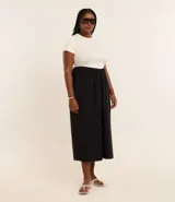 Vestido midi bicolor, con parte superior color crema y falda negra, confeccionado en tejido de punto rib de algodón. Tiene escote redondo y mangas cortas.