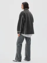 Jean de mujer, tiro medio, corte flare (campana) con estampado de rayas verticales en tonos gris oscuro y verde grisáceo. Confeccionado en denim 100% algodón.