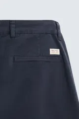 Pantalón chino color beige, corte skinny fit, confeccionado en tejido con mezcla de algodón y elasticidad. Cuenta con bolsillos frontales y traseros. Cierre frontal con cremallera y botón.