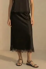 Falda midi negra de satén con encaje en el ruedo.