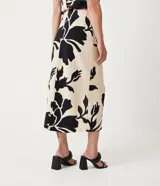 Pollera midi color beige con estampado floral negro, lazo en la cintura y tajo lateral.