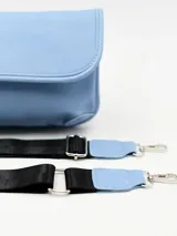 Bandolera azul pastel con correa ancha de tela negra ajustable.