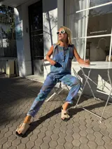 Mono largo de jean con estampado de hojas en tonos azules, marrones y verdes. Tiene botones frontales, corte vintage y bolsillos laterales.