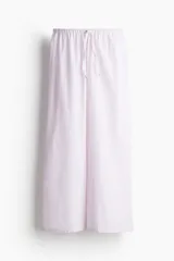Pantalón de pijama de corte holgado en algodón a rayas verticales color lila y blanco. Modelo de tiro bajo con elástico revestido en la cintura y cordón para ajustar.