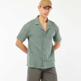 Camisa verde de manga corta con cuello de remera y cierre con botones.