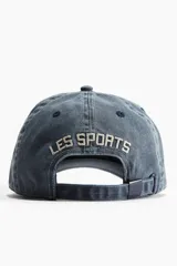Gorra de algodón color azul denim con visera curva y bordado frontal con la inscripción "Paris Sports Club 1972".