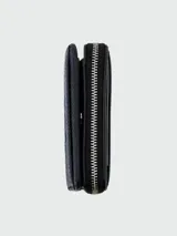 Billetera compacta con cierre de cremallera, color rosa pálido, con textura de cuero granulado y el texto "THE WALLET MARC JACOBS" estampado en el frente.