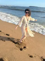 Túnica larga de gasa color beige claro, con mangas largas y cuello en V, con detalle de amarre frontal.