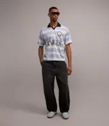 Remera masculina con cuello polo y manga corta, confeccionada en tejido con tecnología dry y estampado a rayas con lettering. Diseño boxy sportcore con cuello polo negro.