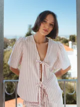 Camisa rosada a rayas verticales grises, con escote en V, mangas 3/4 voluminosas y cierre con lazo.