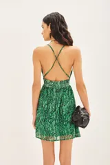 Vestido corto bretelero con estampado reptil en tonos verdes, confeccionado en gasa con lurex y forrería a tono. Cuenta con aplique metálico en el escote, espalda baja con breteles cruzados regulables y elástico en la cintura.