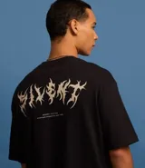 Remera negra de corte relajado, confeccionada en algodón más sostenible, con cuello redondo, manga corta y estampa frontal con un diseño abstracto y la frase "Regret Nothing".