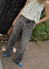 Pantalón jean azul oscuro, de corte wide leg y tiro medio. Presenta detalles de costuras diagonales en la parte superior.