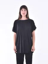 Blusa negra de corte holgado y mangas cortas, con textura plisada.