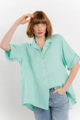 Camisa color verde agua, confeccionada en lino, de corte amplio, con cuello camisero, botones en el frente y mangas 3/4 que se pueden arremangar.