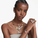 Colgante con cadena dorada y dije en forma de flor con pétalos de cristal azul, centro de cristal amarillo y detalle de cristal celeste en el tallo.