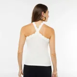 Camiseta de tirantes blanca con cuello halter cruzado y detalle de volados en el escote.