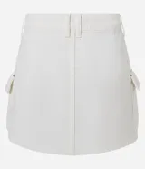 Minifalda cargo color blanco, confeccionada en sarga de algodón, con trabillas, bolsillos laterales y cierre frontal con botón.