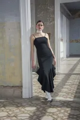 Vestido negro de corte sirena con volados en el ruedo y breteles finos. Diseño ajustado al cuerpo.