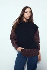 Chaleco tejido sin mangas de color negro, con cuello redondo y diseño de textura sutil. Presenta un corte recto con terminaciones acanaladas en el ruedo y hombros levemente estructurados.