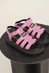 Sandalias de cuero sintético color lila con plataforma negra y tiras anchas cruzadas.