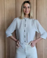 Camisa color beige claro con cuello con volados y mangas 3/4 abullonadas.