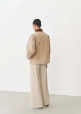 Chaqueta color beige de algodón con cuello marrón de pana, cierre frontal con botones, corte recto, manga larga y cuatro bolsillos frontales.