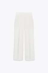 Pantalón de tiro alto color blanco, de corte recto y pierna ancha, con bolsillos laterales y pinzas frontales.
