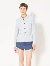 Chaqueta corta de jacquard chanel color celeste, con cuello redondo y cierre frontal con botones marrones. Presenta detalles de flecos en el escote, bolsillos delanteros inferiores y sisas.