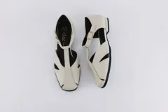 Zapatos bajos rojos de cuero, con puntera redondeada y tira central con hebilla. Presentan aberturas laterales.