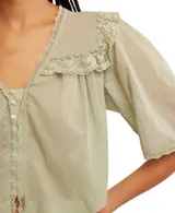Blusa blanca de algodón con escote en V, mangas cortas y detalle de bordado tipo encaje.