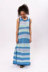 Vestido largo de algodón tejido a rayas horizontales en tonos celeste, azul y verde agua. Diseño holgado con cuello redondo y aberturas laterales en el ruedo.