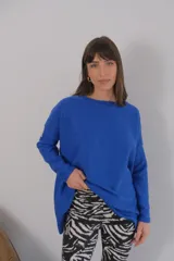 Buzo azul de viscosa con cuello redondo y manga larga. Presenta un aplique con diseño geométrico en el brazo izquierdo.