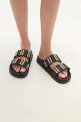 Sandalias tipo slide de plataforma color marrón, con dos tiras anchas sobre el empeine decoradas con tejido de rafia en tonos marrón, negro y beige.