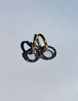 Par de aros colgantes con argollas doradas y dijes circulares de resina transparente con incrustaciones de strass de colores. El dije mide aproximadamente 1.5cm de diámetro.