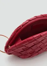 Bolso de mano pequeño confeccionado en piel ovina con diseño trenzado en color bordó. Presenta una forma de media luna, cierre a presión y forro interior de algodón. Incluye un detalle de aro metálico dorado en el lateral.