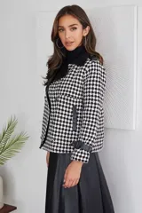 Campera corta con estampado pata de gallo en blanco y negro, cuello y puños de cuero sintético negro, doble botonadura y corte holgado.