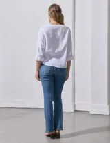 Blusa de algodón a rayas verticales finas en tonos blanco y lila, con escote en V, abertura frontal con botones y mangas largas regulables con presilla y botón. El ruedo termina anudado al frente.