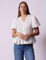 Blusa blanca de algodón con bordado broderie, escote en V con abertura central y botones, cintura elastizada y mangas cortas con terminación elastizada.