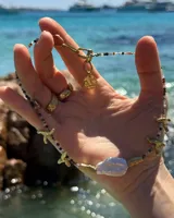 Collar corto con cuentas de piedra natural multicolor, perlas de río irregulares y dijes de bronce con forma de coral.