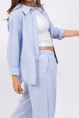 Camisa a rayas verticales color beige y blanco, con cuello clásico, cierre frontal con botones y mangas largas.