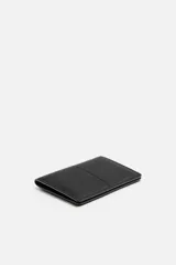 Tarjetero negro de cuero con costura central y cuatro ranuras para tarjetas.