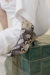 Bota corta de cuero vacuno con estampado animal print serpiente en tonos blanco y negro, con puntera fina y cierre trasero. Tiene taco chupete y suela de cuero.