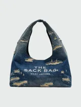 Bolso de hombro Marc Jacobs modelo The Sack Bag, confeccionado en denim azul con efecto desgastado y roturas. Presenta el logo de la marca estampado en el frente.