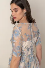 Vestido largo de gasa color marfil con bordado de hilo de seda en tonos celeste y avena. Modelo recto con corte en la cintura, manga corta y ruedo terminado en blonda.