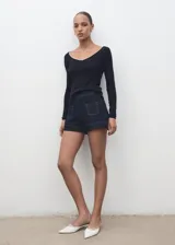 Camiseta ajustada de manga larga, color negro, con escote pico ribeteado en blanco.