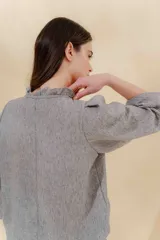Blusa color beige con cuello mao con volantes, manga larga con puño elástico y cierre frontal con botones ocultos.