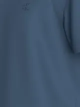 Remera azul de algodón con cuello redondo y mangas cortas. Presenta un pequeño logo CK bordado en el pecho y un monograma de Calvin Klein texturizado en la espalda.